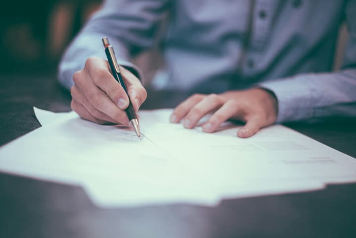 Documents imprimés, un stylo et des lunettes sur un bureau.