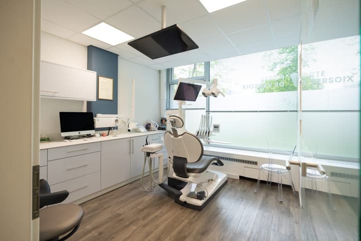 Salle de soins du Centre Dentaire Lancy Bachet : fauteuil dentaire, écran chairside et paroi vitrée dépolie.